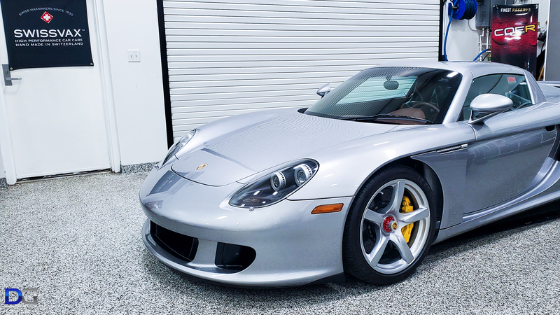 Silver Porsche Carrera GT in a garage, showing off yellow brake calipers.