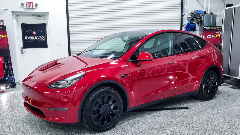 Red Tesla Model Y with black wheels parked indoors.