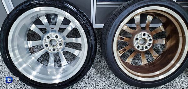 Two car wheels, one clean and shiny, the other dirty and corroded, side-by-side on a grey surface.