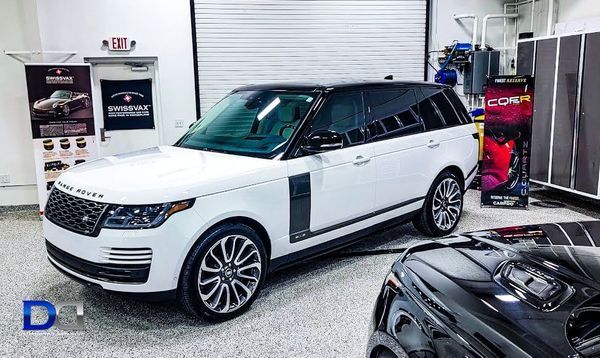 White Range Rover SUV parked inside a garage, with black accents and wheels.