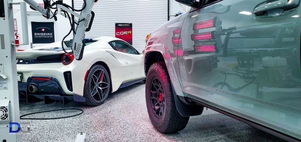 A white Ferrari sports car and a gray SUV in a garage.