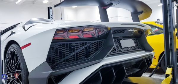 White Lamborghini Aventador rear view with a large black spoiler, in a garage.