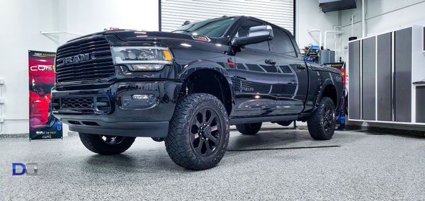 Black Ram truck parked in a garage with dark gray wheels and a glossy paint job.