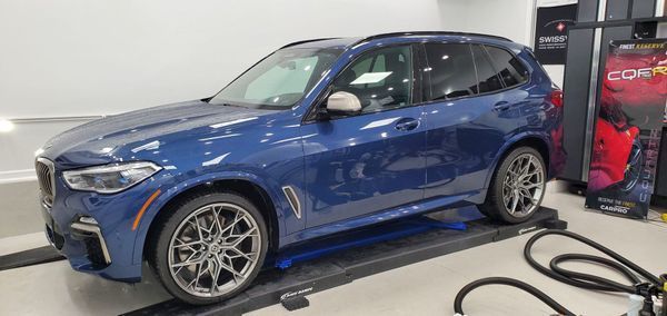 A blue BMW X5 SUV on a lift in a garage.