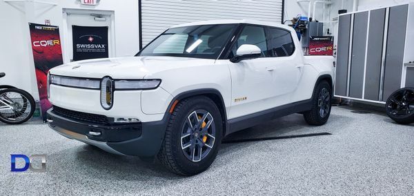 White Rivian pickup truck parked inside a garage.