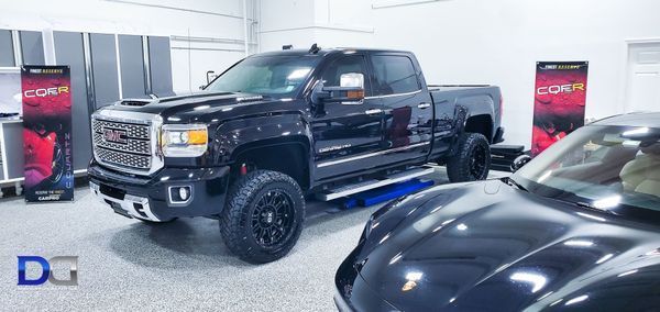 Black GMC truck in a garage next to a black sports car.