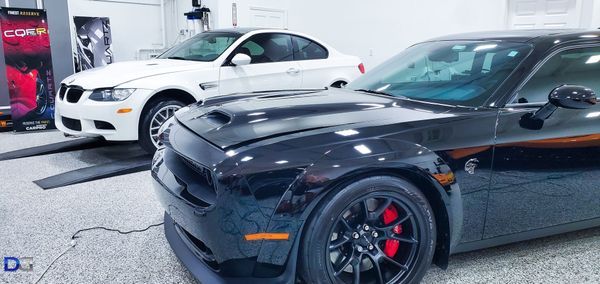 Black Dodge Challenger and white BMW in a garage.
