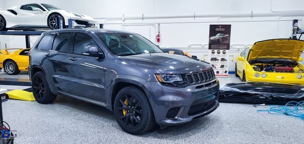 Gray Jeep SUV in a garage with sports cars.