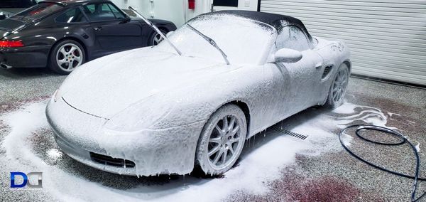 White convertible car covered in foam. Another car behind it. Indoors.
