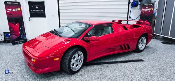 Red Lamborghini Diablo parked in a garage with banners on the wall.