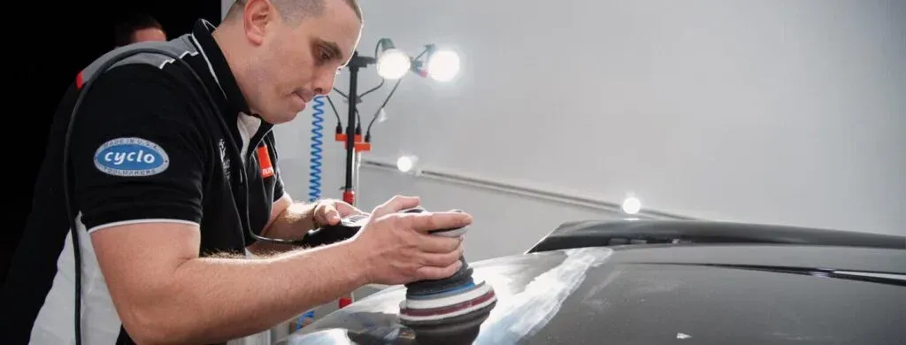 A man is polishing a car with a machine.