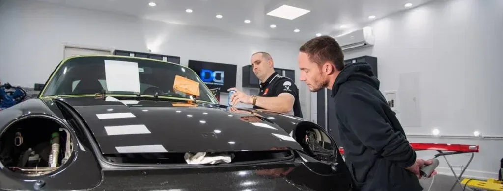 Two men are working on a car in a garage.