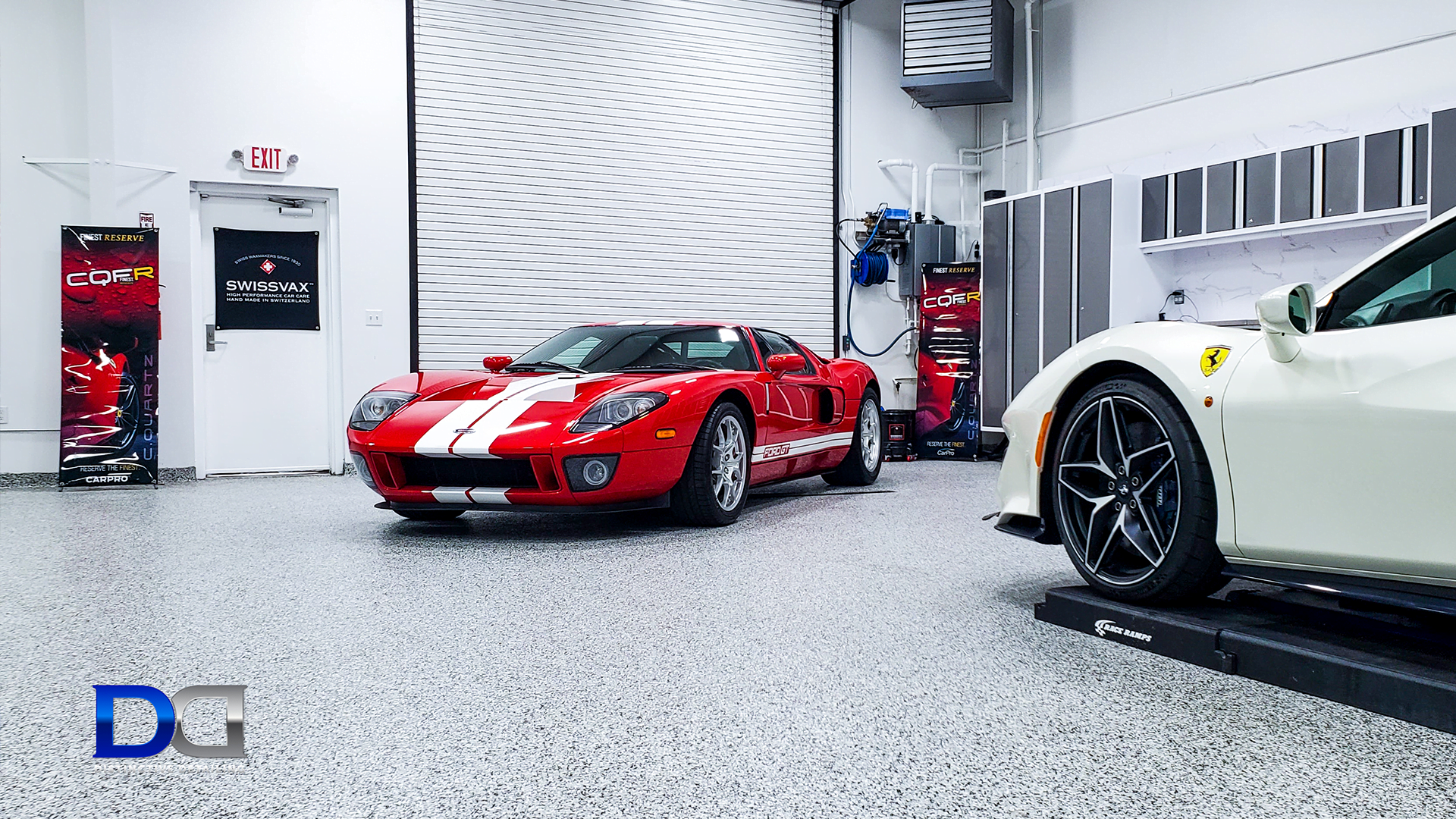 Red Ford GT and white Ferrari in a well-lit garage with a speckled floor.