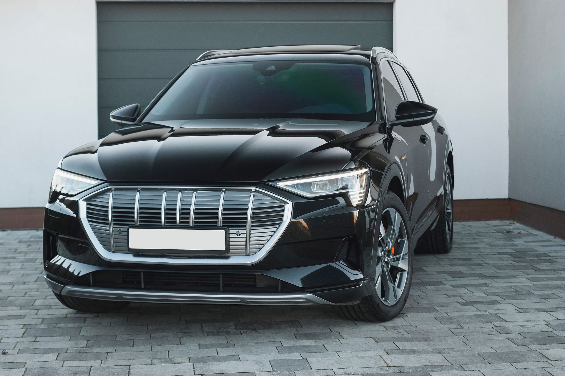 A black car is parked in front of a garage door.