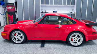 Red Porsche 911 sports car on a lift in a garage.