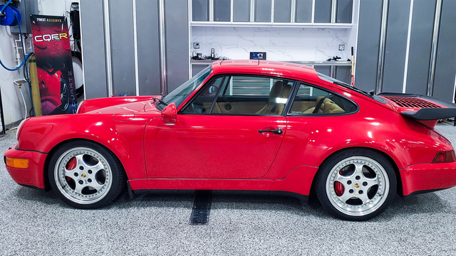 Red Porsche 911 sports car on a lift in a garage.