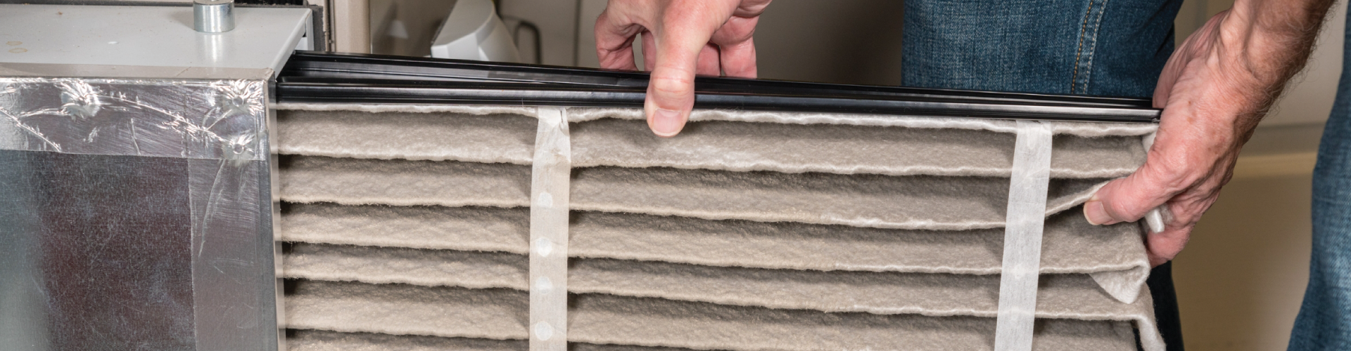 A person is holding a dirty air filter in their hands.