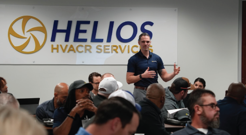 A man is giving a presentation to a group of people in front of a helios hvacr service sign.