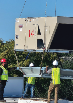 A crane is lifting an HVAC Unit onto a rooftop