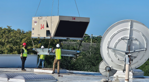 A crane is lifting an HVAC Unit with the number 14 on it to a rooftop