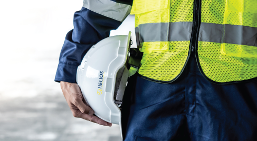 A man in a safety vest is holding a hard hat.