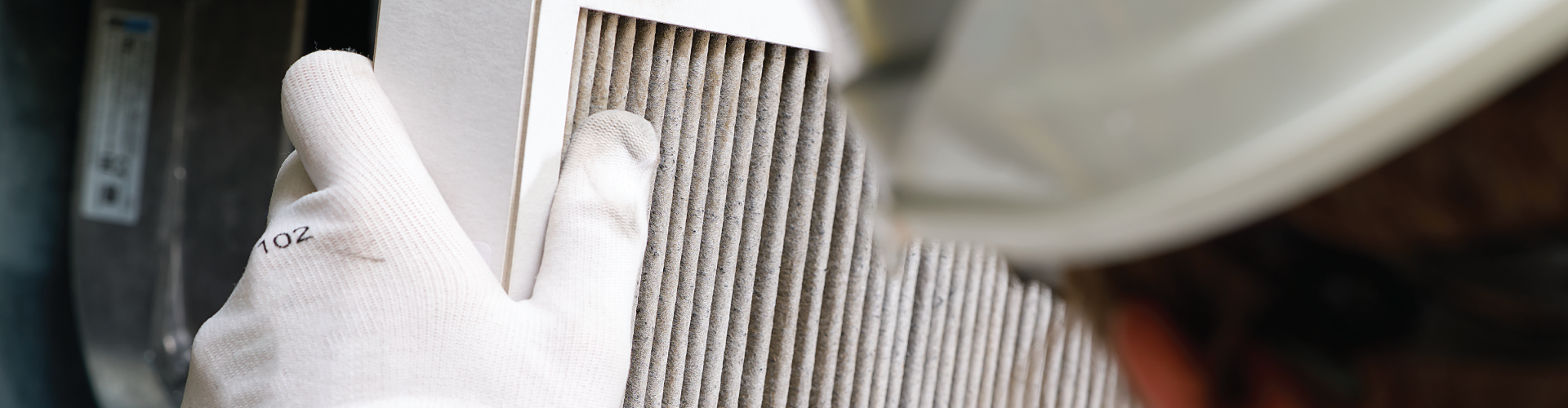 A person wearing white gloves is holding a filter in their hand.