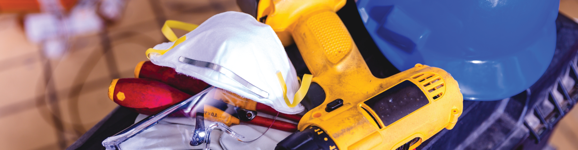 A close up of a drill and a hard hat on a table.