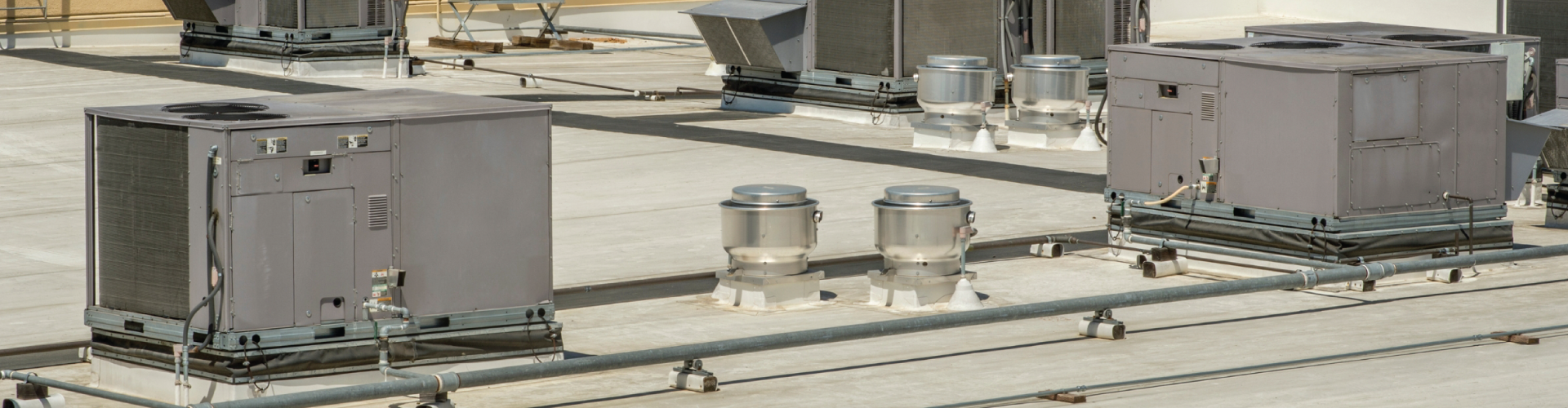 A row of air conditioners are sitting on top of a roof.