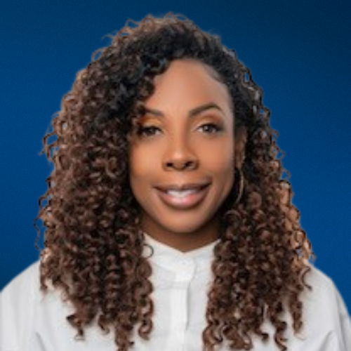 A woman with curly hair is wearing a white shirt and smiling.
