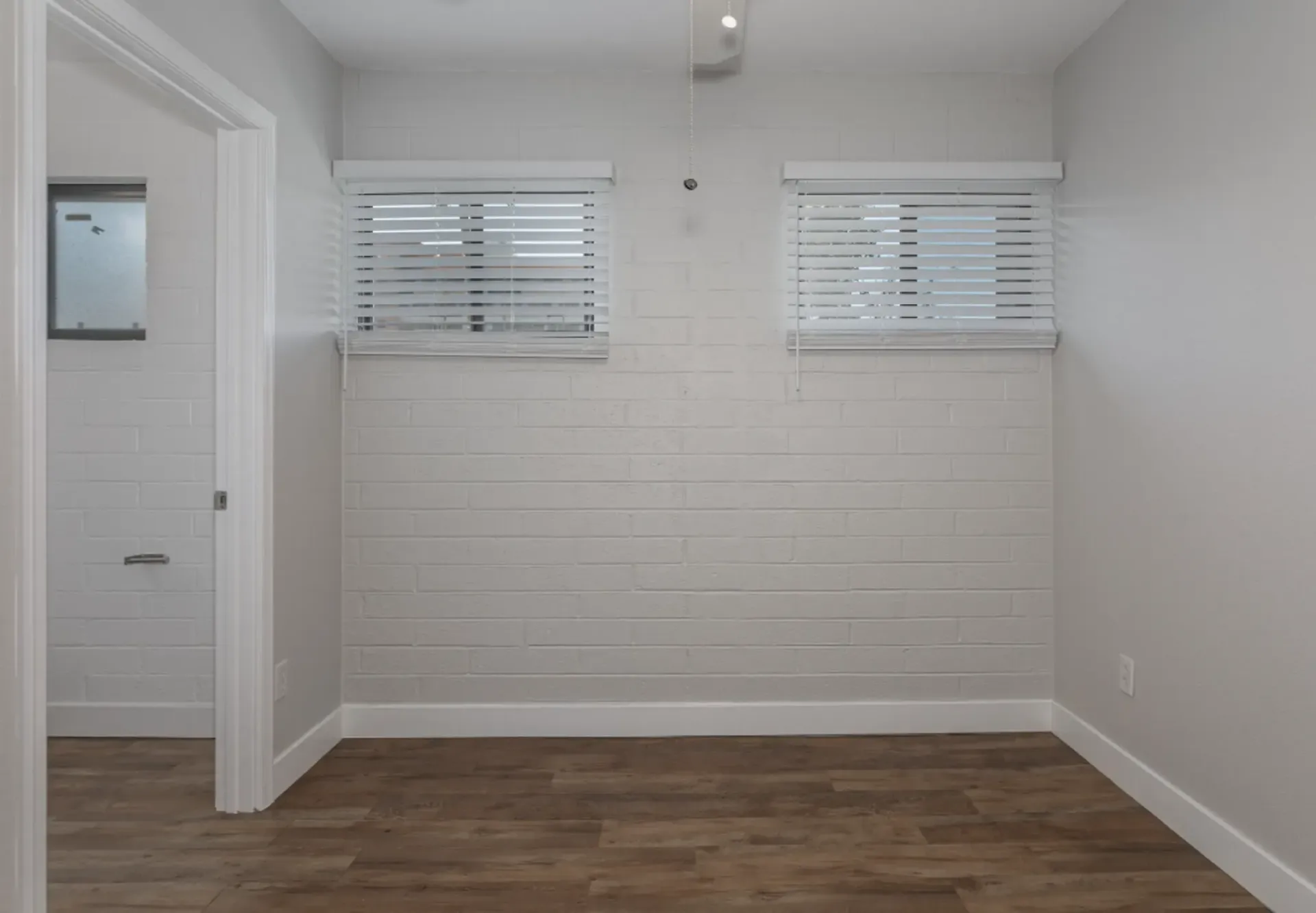 an empty room with white blinds on the windows