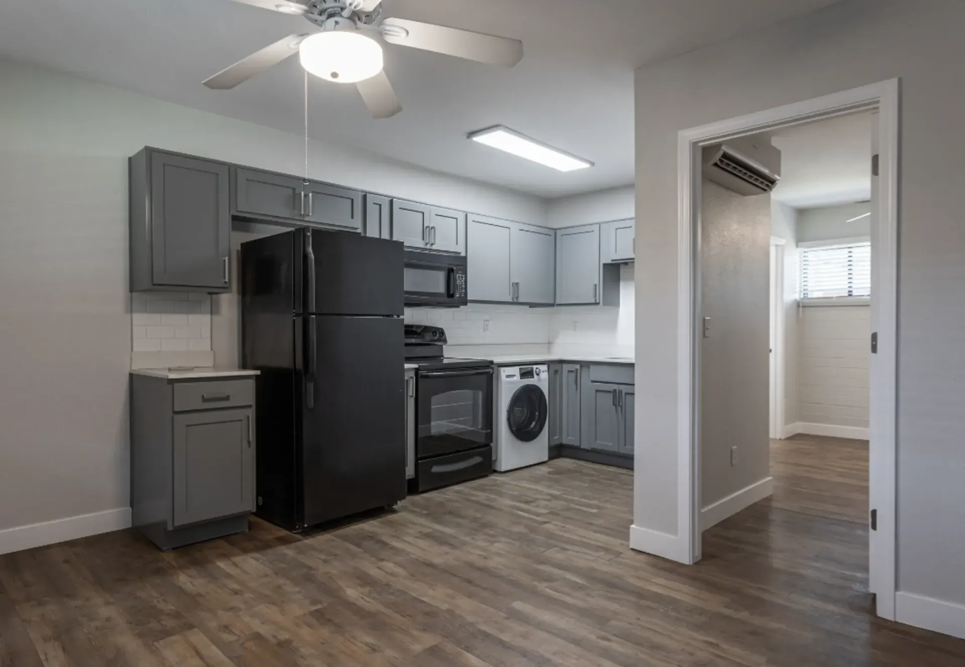 a kitchen with a black refrigerator and grey cabinets