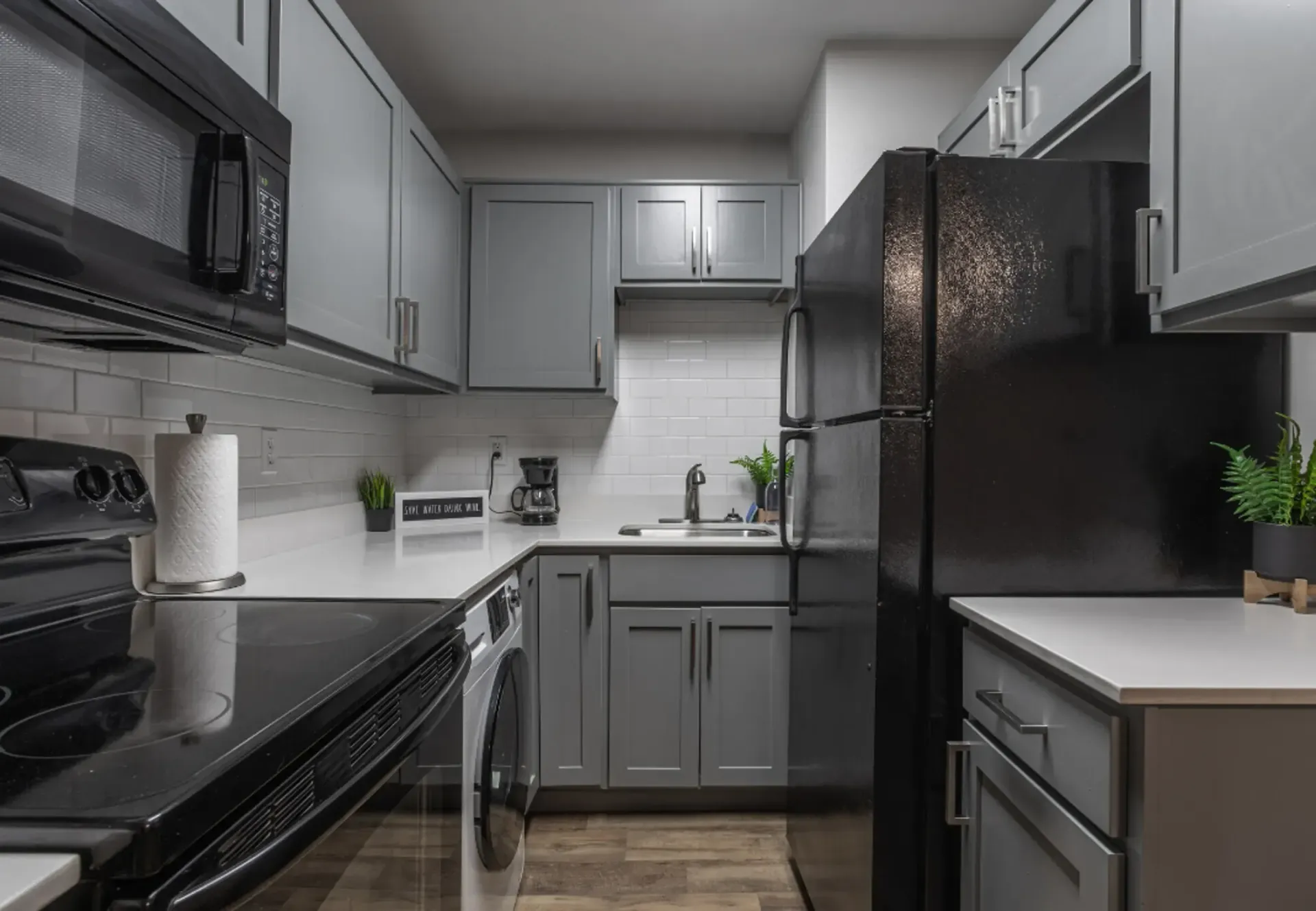 a kitchen with gray cabinets and black appliances