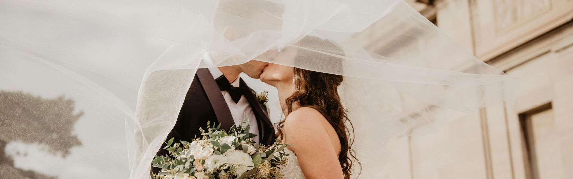 Bride and groom kissing under a wedding veil