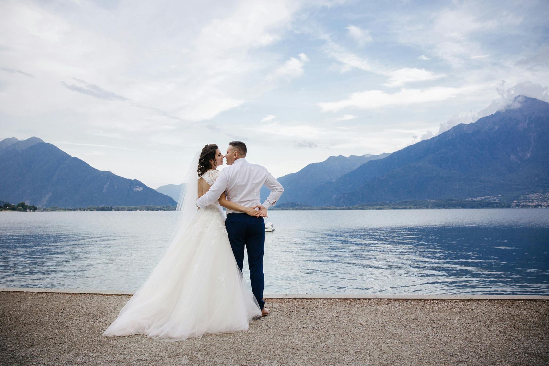 Bride and groom on a beach with mountain landscape.