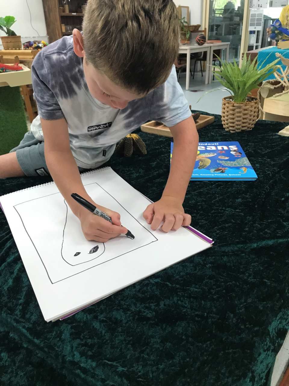 A young boy is drawing on a piece of paper with a marker