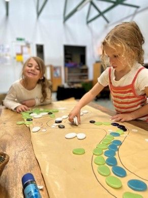 Two little girls are sitting at a table playing with rocks.