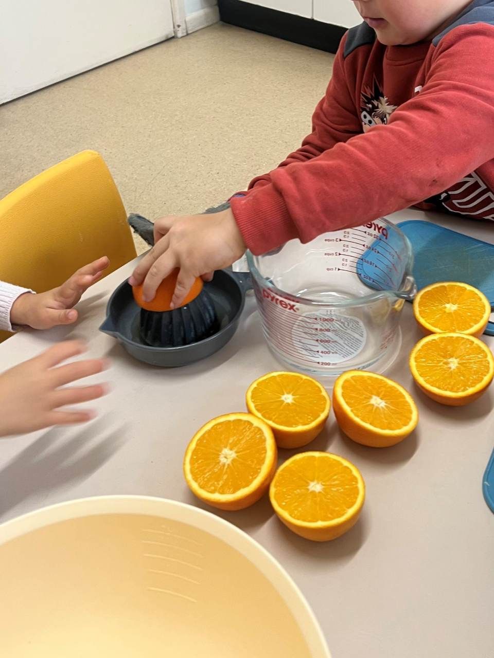 A little boy is squeezing oranges with a brush