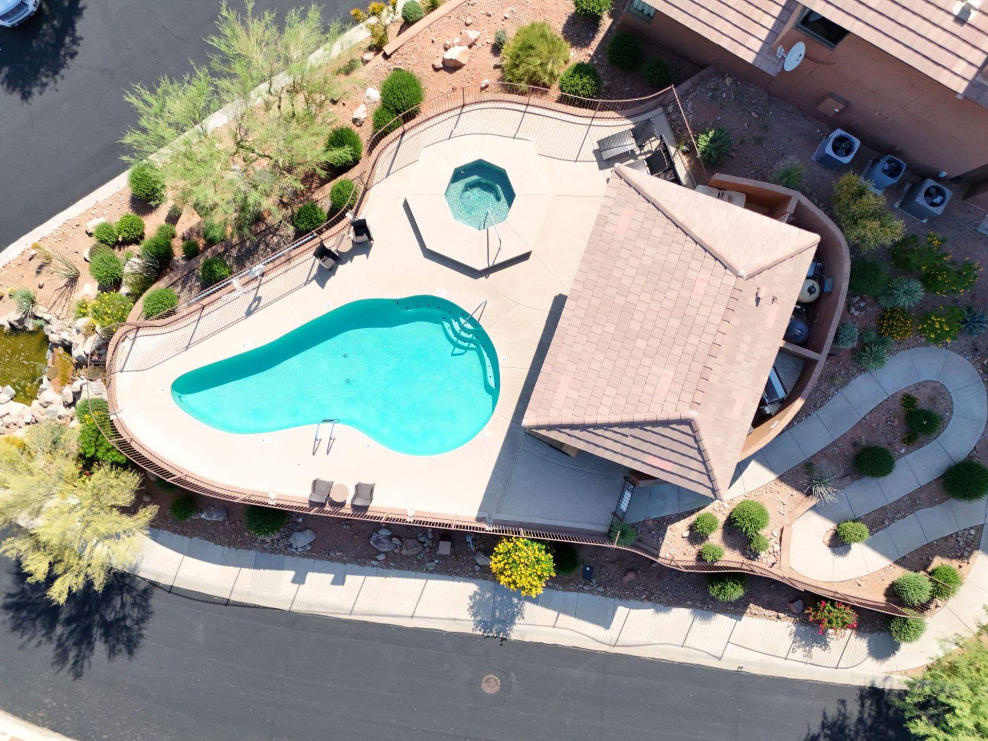 Aerial view of a house with a pool and hot tub in a desert setting.