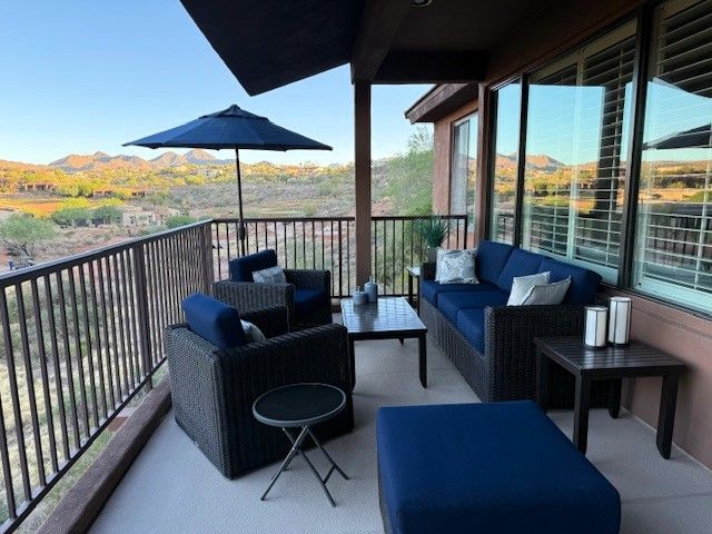 Patio with blue furniture, umbrella, and view of mountains.