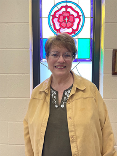 A woman standing in front of a stained glass window
