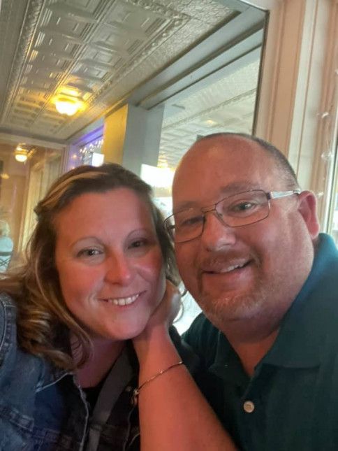 A man and a woman are posing for a picture and smiling for the camera.