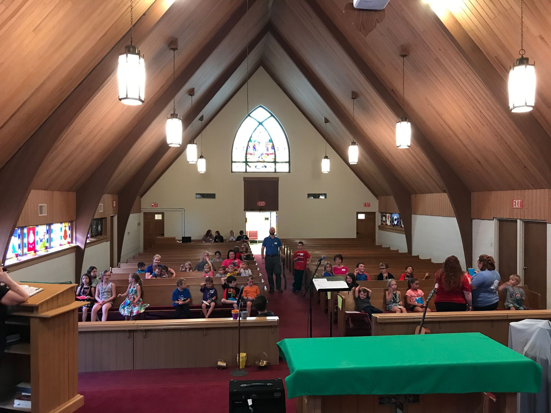 A group of people are sitting in a church with a green table in front of them