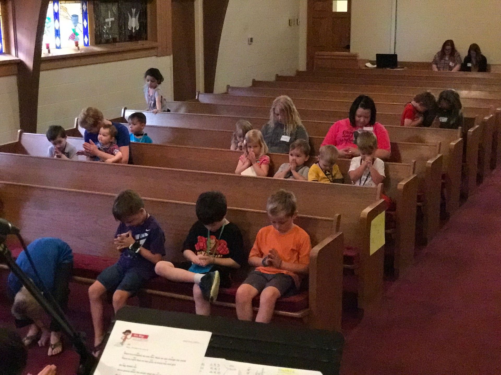 A group of children are sitting in a church looking at their phones
