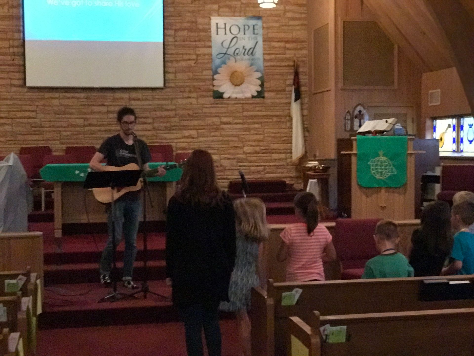 A man playing a guitar in front of a sign that says hope and lord