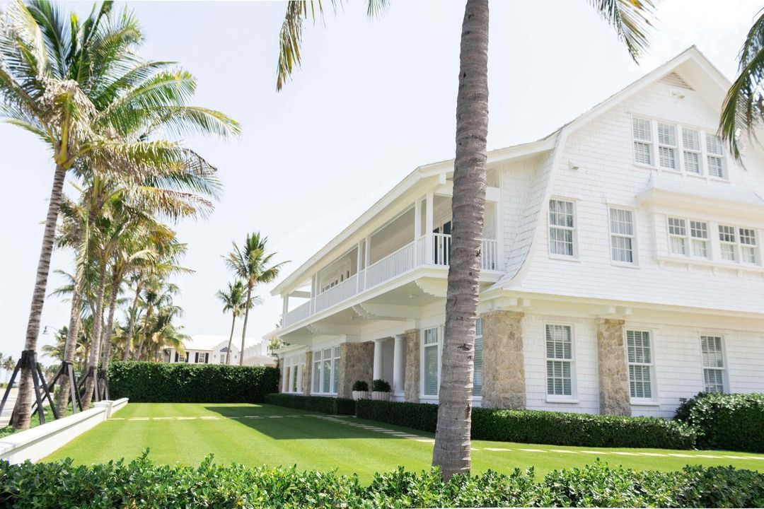 A large white house withnew palm trees in front of it