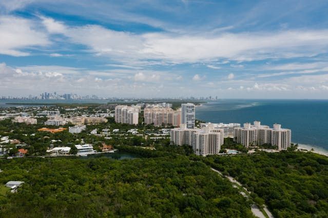 An aerial view of Miami-Dade county surrounded by trees and buildings next to the ocean.