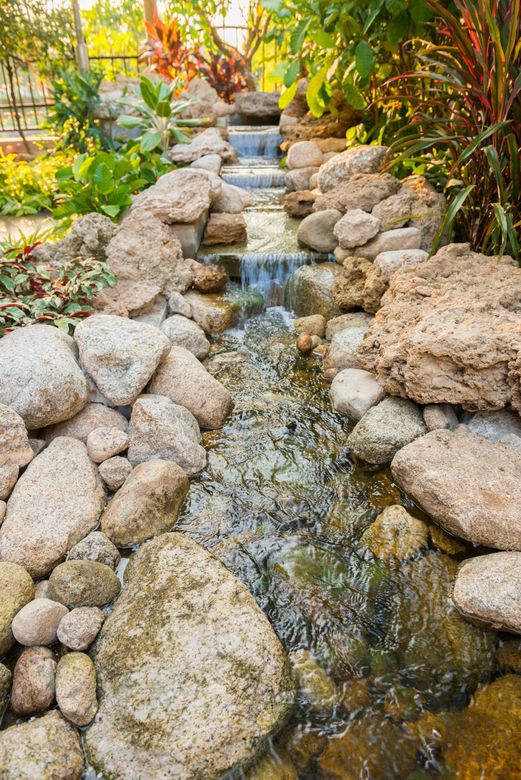 A small waterfall is surrounded by rocks in a garden.