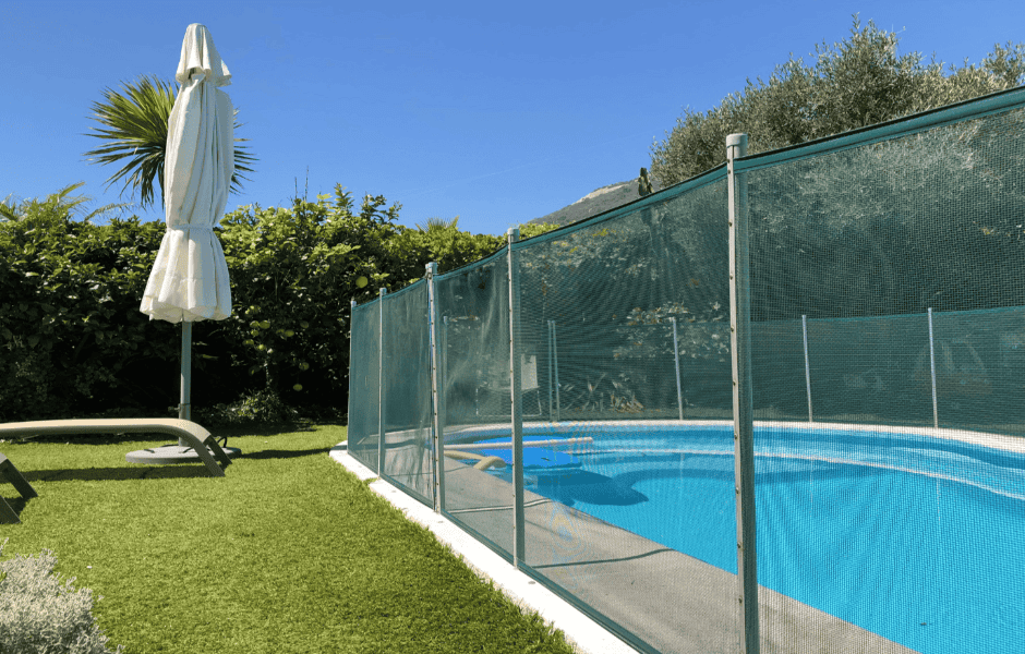 A swimming pool surrounded by a safety fence in a backyard.