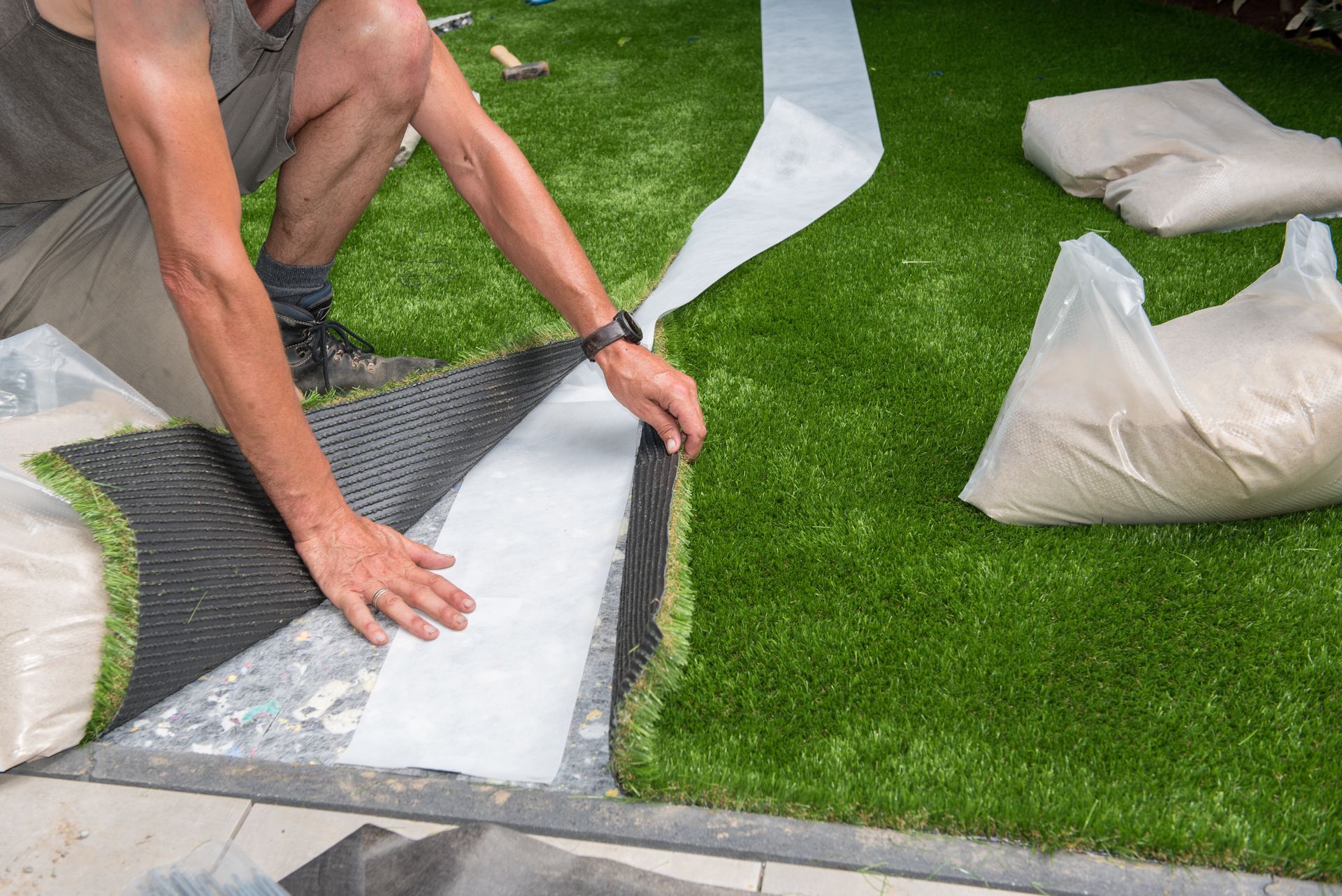 Turf experts crouching down to measure and lay artificial grass