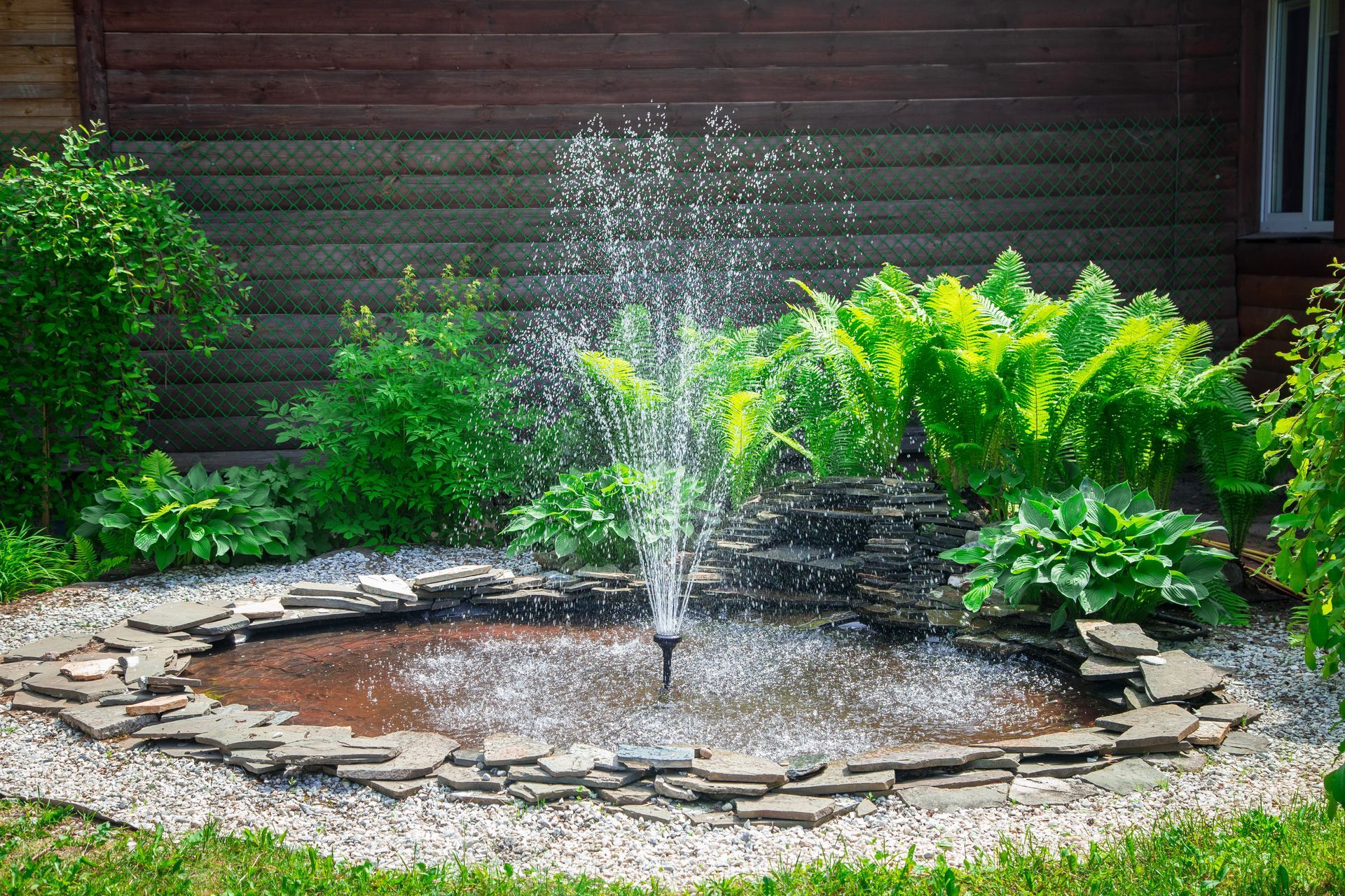 Backyard fountain surrounded by stone, tile, and greenery 